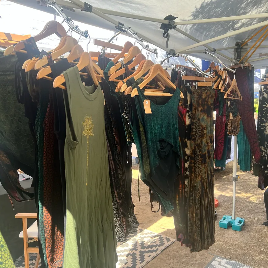 Earth-toned festival clothing hanging on wooden racks at the Rapt with Joy stall.