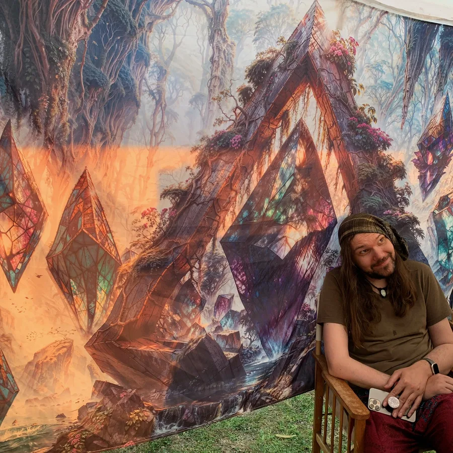 Visionary tapestry with crystal forms hanging at a festival setup.