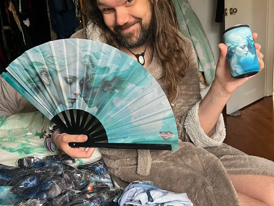 Michael/Krip holding a fan in front of colourful Rapt with Joy textiles.
